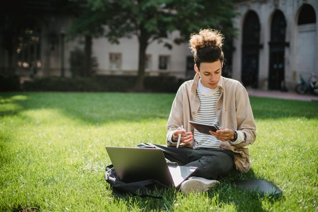 serious male student reading notebook while doing university task